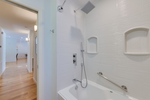 bathroom with hardwood / wood-style floors and tiled shower / bath