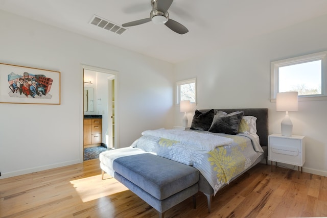 bedroom featuring multiple windows, ceiling fan, ensuite bath, and light hardwood / wood-style floors