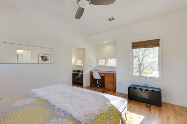 bedroom with built in desk, ceiling fan, and light hardwood / wood-style floors