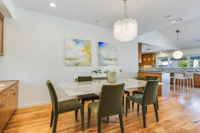 dining space featuring vaulted ceiling, light hardwood / wood-style flooring, and a notable chandelier