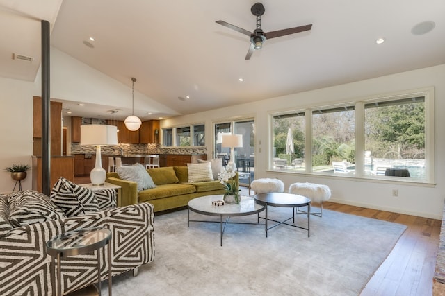 living room featuring ceiling fan, lofted ceiling, and light hardwood / wood-style floors