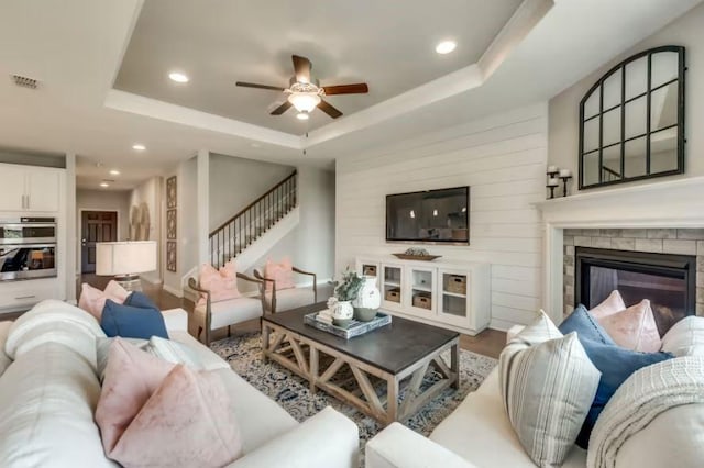 living room with hardwood / wood-style floors, ceiling fan, and a tray ceiling