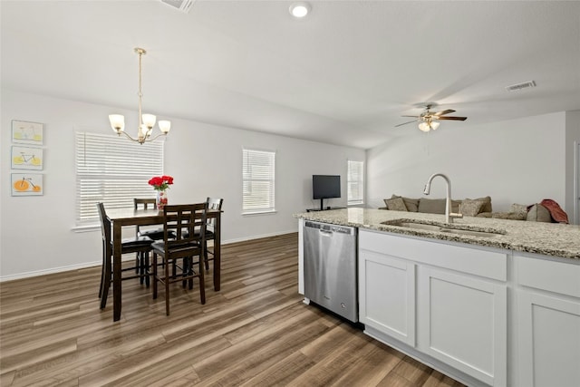 kitchen with sink, white cabinetry, light stone countertops, decorative light fixtures, and stainless steel dishwasher