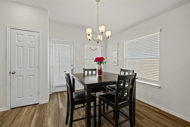 dining space featuring dark wood-type flooring and an inviting chandelier