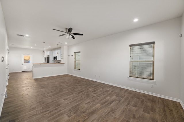 unfurnished living room featuring ceiling fan and dark hardwood / wood-style flooring