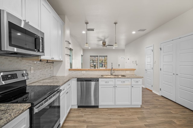 kitchen featuring sink, white cabinetry, decorative light fixtures, kitchen peninsula, and stainless steel appliances