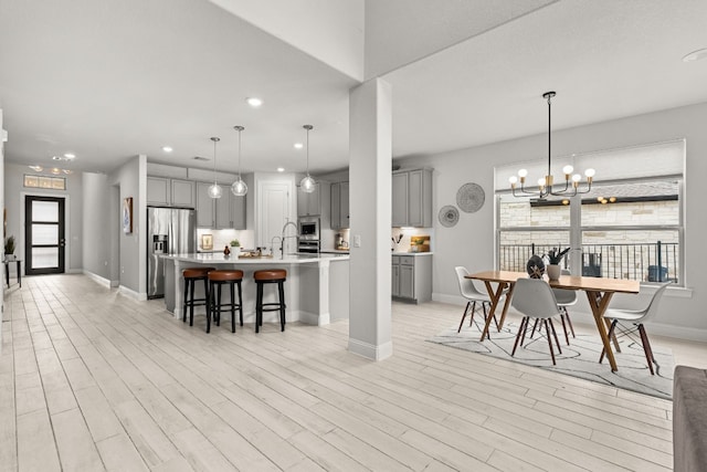 interior space featuring a large island, pendant lighting, gray cabinets, a breakfast bar, and appliances with stainless steel finishes