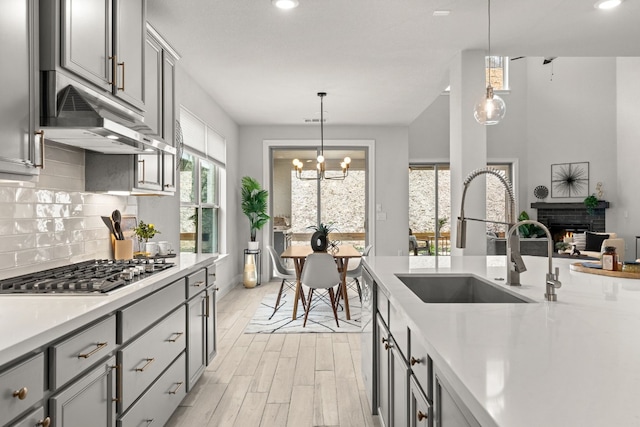 kitchen with pendant lighting, sink, gray cabinetry, and stainless steel gas stovetop