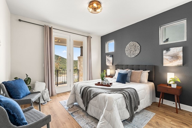 bedroom with access to exterior and light hardwood / wood-style floors