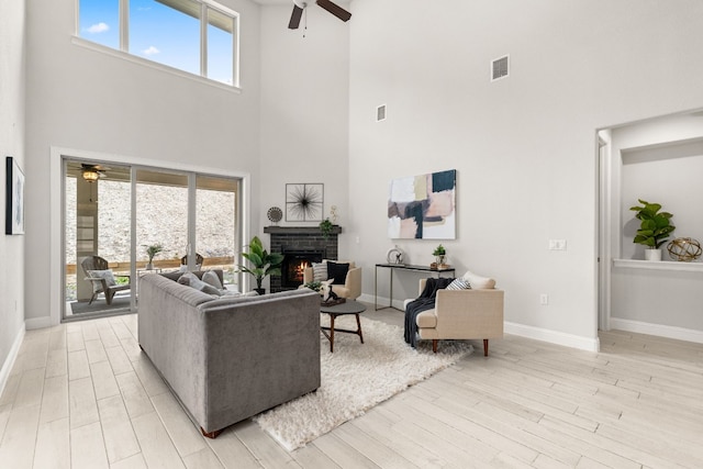 living room featuring a towering ceiling, plenty of natural light, and a brick fireplace