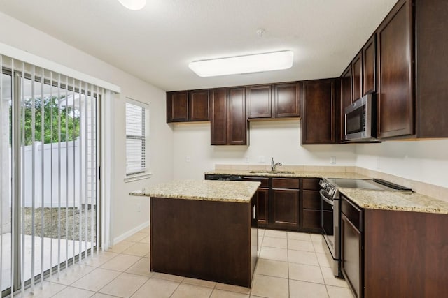 kitchen with appliances with stainless steel finishes, sink, a kitchen island, and light tile patterned floors