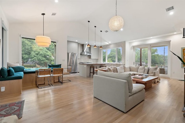 living room featuring high vaulted ceiling and light hardwood / wood-style flooring