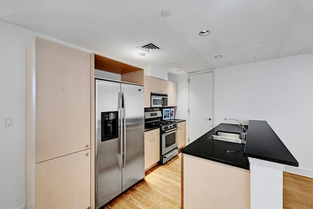 kitchen with sink, light wood-type flooring, kitchen peninsula, and appliances with stainless steel finishes