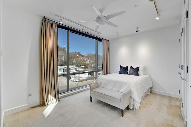 carpeted bedroom featuring a wall of windows, rail lighting, and ceiling fan