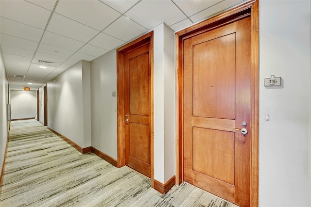 hallway with a paneled ceiling and light wood-type flooring