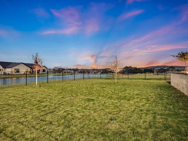 yard at dusk featuring a water view