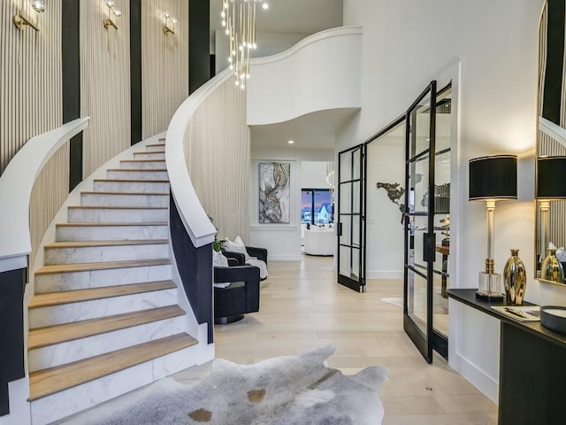 stairway with a high ceiling, hardwood / wood-style floors, and french doors