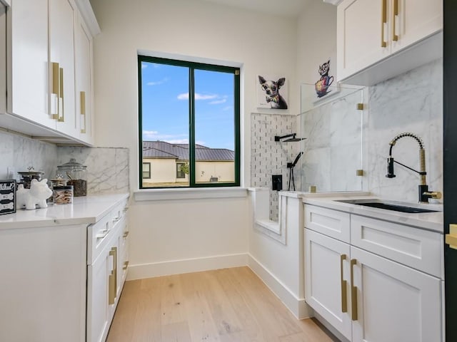 kitchen featuring white cabinetry, backsplash, light hardwood / wood-style floors, and sink