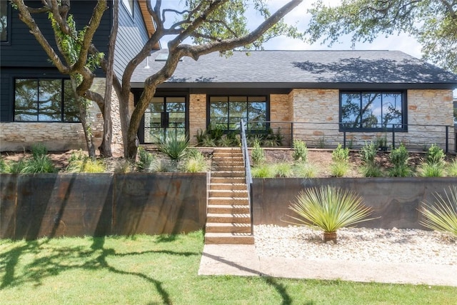 property entrance featuring roof with shingles and stone siding