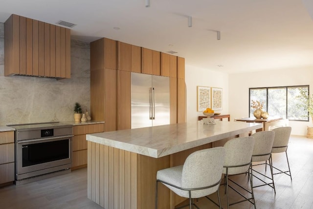 kitchen featuring light hardwood / wood-style floors, a breakfast bar area, stainless steel appliances, and a center island