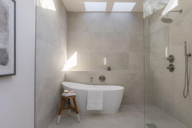 bathroom featuring tile walls, a skylight, and separate shower and tub