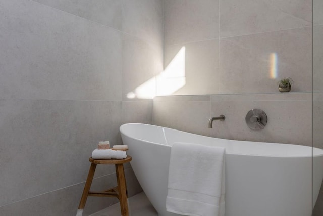 bathroom featuring a freestanding tub and tile walls