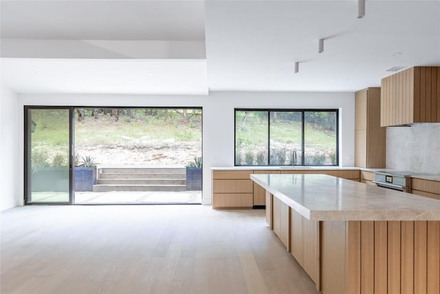 kitchen with sink, light hardwood / wood-style flooring, a center island, extractor fan, and light brown cabinets