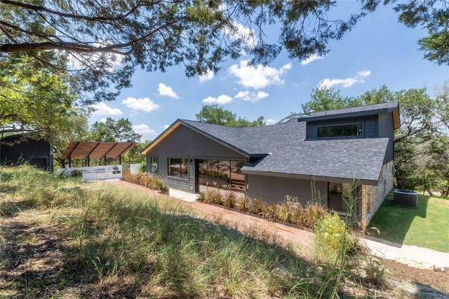 view of front of home with cooling unit and a shingled roof