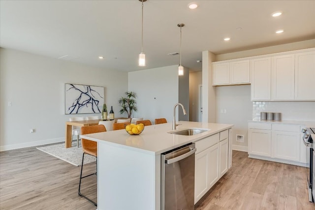 kitchen with white cabinetry, stainless steel appliances, sink, and a center island with sink