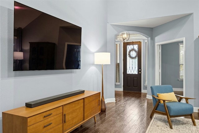 foyer entrance with dark wood-style floors, baseboards, and an inviting chandelier