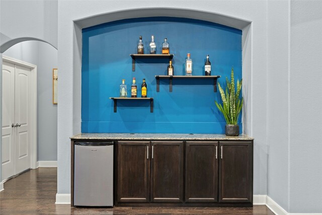 bar featuring fridge, a dry bar, dark wood-style floors, and baseboards