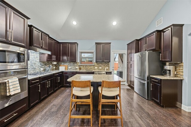 kitchen featuring visible vents, a kitchen island, vaulted ceiling, dark brown cabinets, and appliances with stainless steel finishes