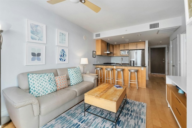 living room with ceiling fan, sink, and light hardwood / wood-style floors