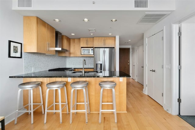 kitchen featuring sink, a breakfast bar area, dark stone countertops, appliances with stainless steel finishes, and kitchen peninsula