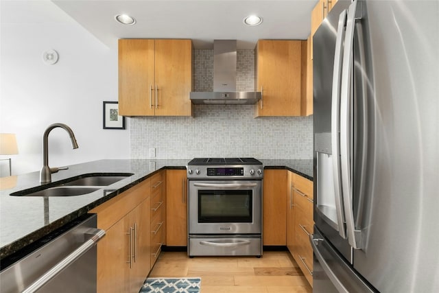 kitchen featuring wall chimney exhaust hood, sink, dark stone countertops, stainless steel appliances, and decorative backsplash