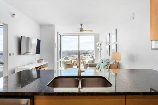 kitchen with ceiling fan, dark stone countertops, sink, and a wealth of natural light