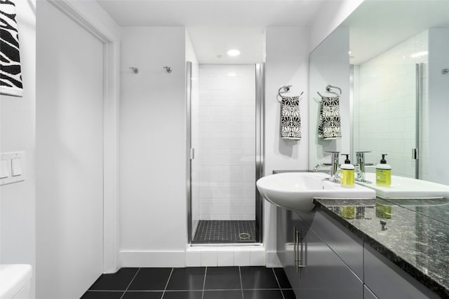 bathroom featuring toilet, vanity, a shower with door, and tile patterned flooring