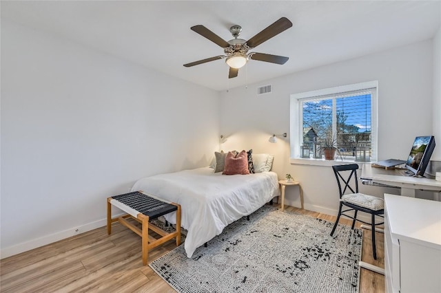 bedroom featuring light wood finished floors, baseboards, visible vents, and a ceiling fan