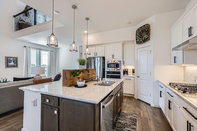 kitchen with stainless steel appliances, hanging light fixtures, a kitchen island with sink, and white cabinets