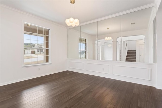 spare room with a healthy amount of sunlight, dark wood-type flooring, and a chandelier