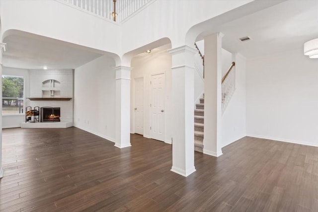 unfurnished living room featuring dark hardwood / wood-style floors and decorative columns