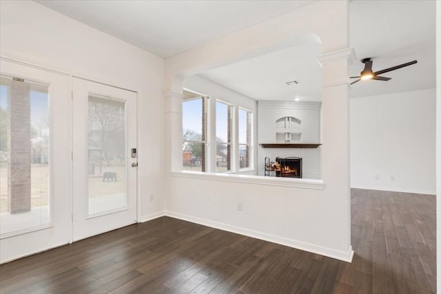 unfurnished living room with dark wood-type flooring, ceiling fan, and a fireplace