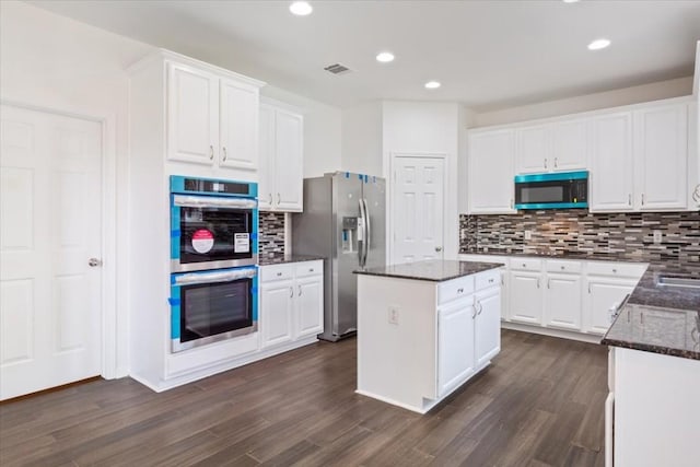 kitchen with a center island, appliances with stainless steel finishes, dark hardwood / wood-style flooring, white cabinets, and backsplash