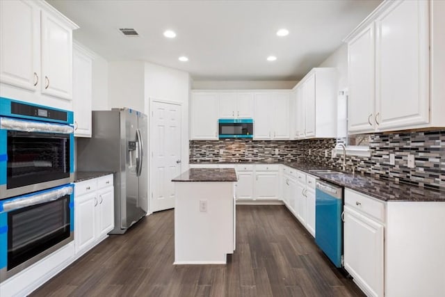 kitchen with sink, appliances with stainless steel finishes, white cabinetry, a center island, and decorative backsplash