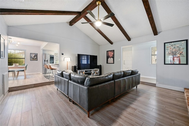 living room featuring vaulted ceiling with beams, a textured ceiling, and ceiling fan