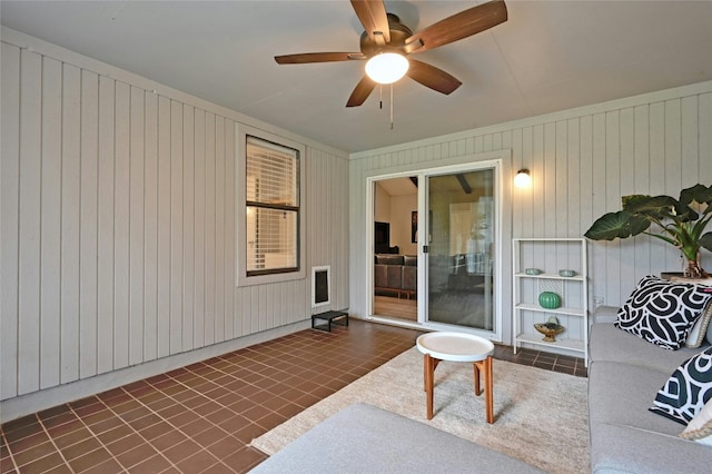 interior space with ceiling fan and wood walls