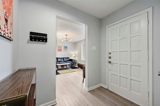 entryway with an inviting chandelier, light hardwood / wood-style flooring, and a textured ceiling