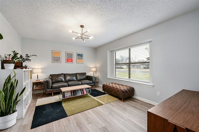 living room featuring a textured ceiling, an inviting chandelier, and light hardwood / wood-style floors