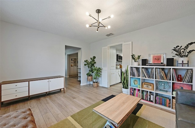 living area with light hardwood / wood-style floors, a chandelier, and a textured ceiling