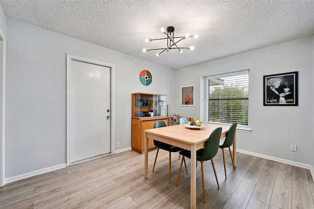 dining area featuring light wood-type flooring, a textured ceiling, and a notable chandelier